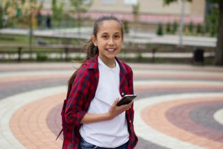 smiling girl holding smartphone in a park